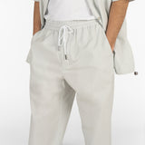 Il modello indossa un pantalone con coulisse e una camicia a maniche corte di colore grigio.