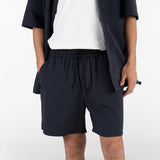 model is wearing seersucker drawstring shorts and seersucker short sleeved shirt in blue colour