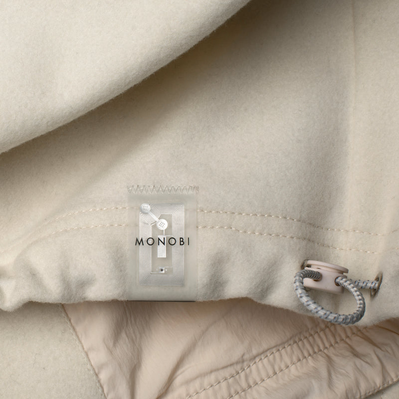 Dettagli della coulisse e dell'etichetta NFC di RESPONSIBLE WOOL COACH JACKET / NATURALE