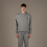 Model wears superior wool loungewear hoodie color grey, front.