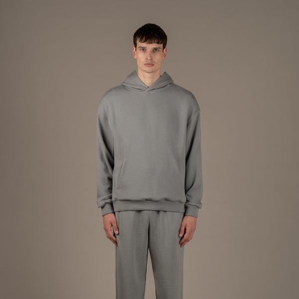 Model wears superior wool loungewear hoodie color grey, front.