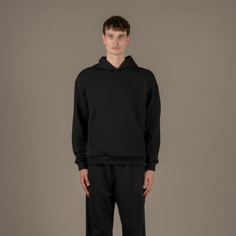 Model wears superior wool loungewear hoodie color black, front