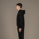 Model wears superior wool loungewear hoodie color black, side.