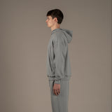 Model wears superior wool loungewear hoodie color grey, side.