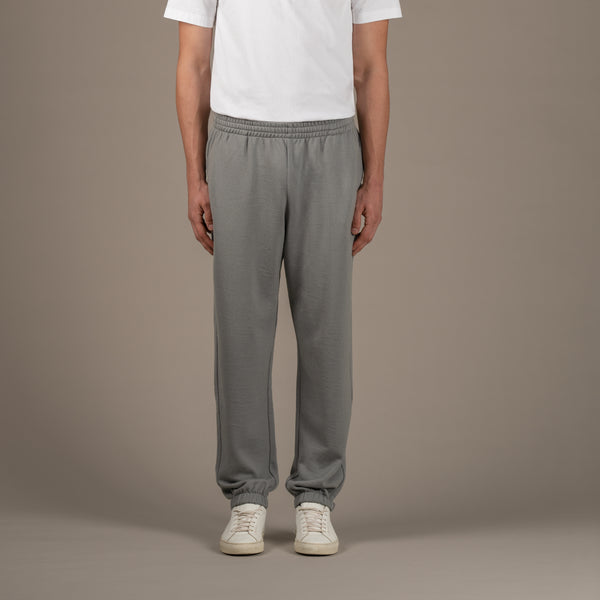 Model wears superior wool loungewear joggers color grey, front.