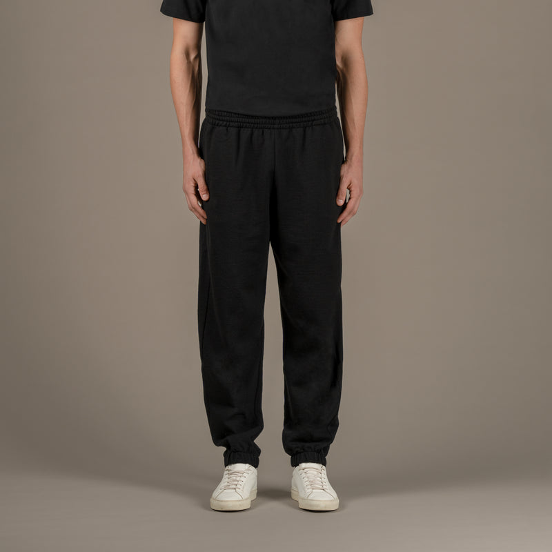 Model wears superior wool loungewear joggers color black, front